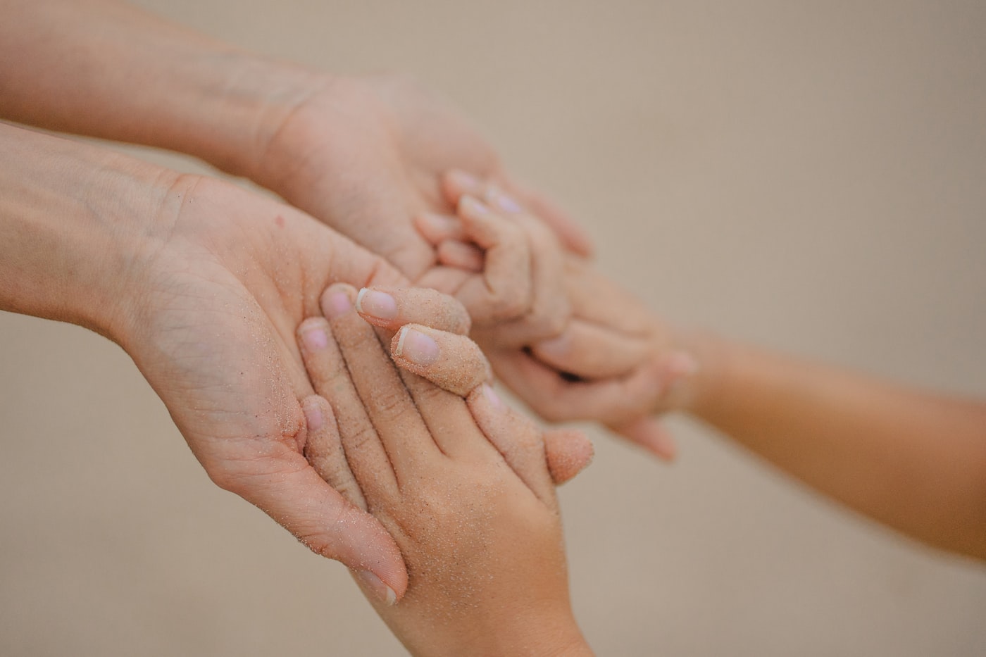 An adult and child's hands holding gently